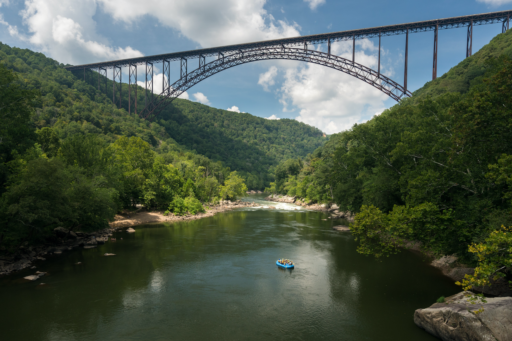 Rafters float towards the rapids under the high arched New River Gorge bridge in West Virginia