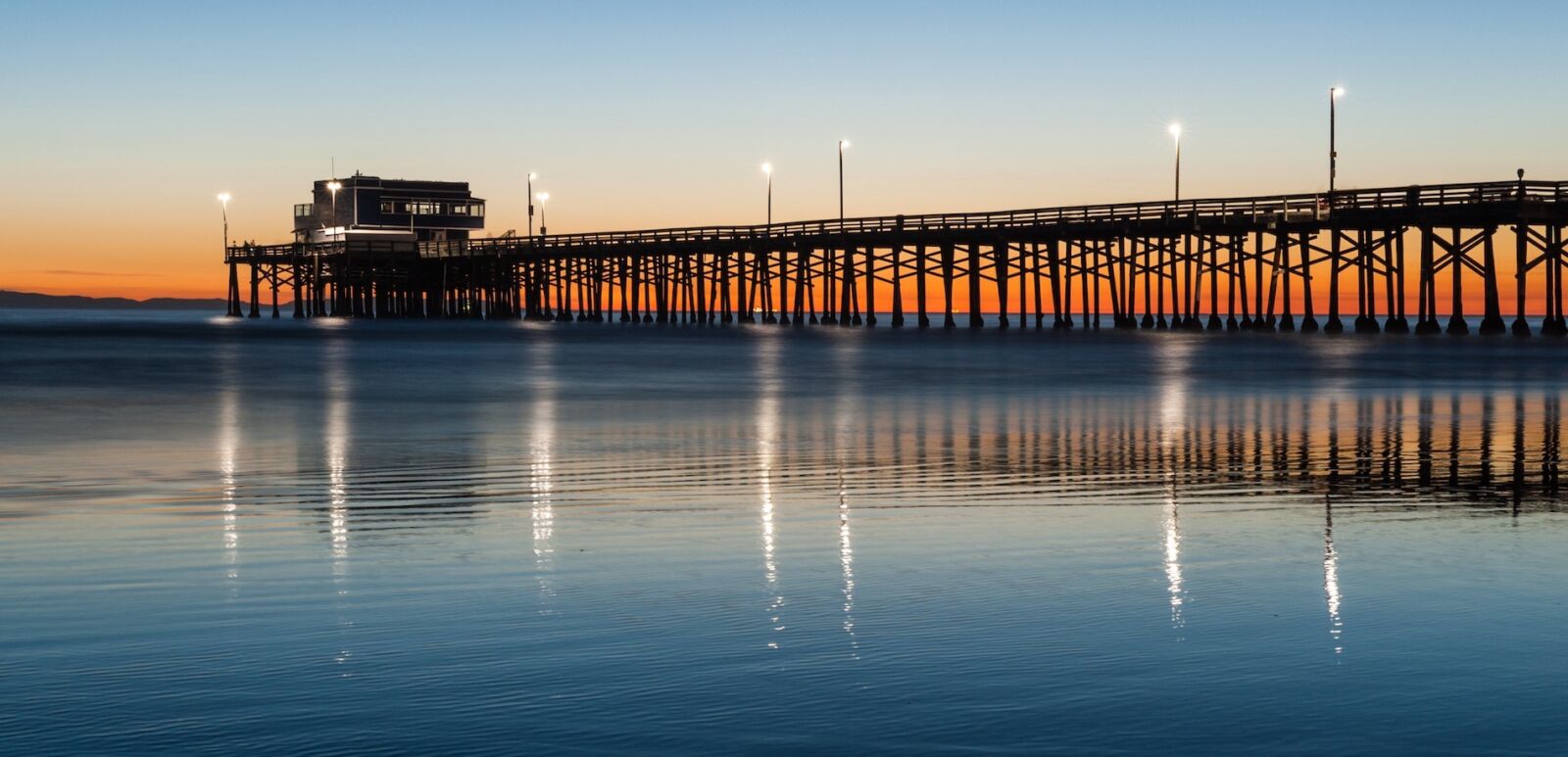 Newport Beach pier silhouette sunset. Photo via Shutterstock.