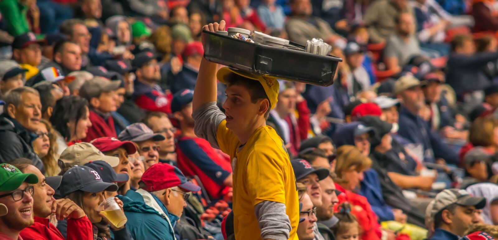 A Fenway Park vendor sells hot dogs to Boston Red Sox fans at a baseball game.