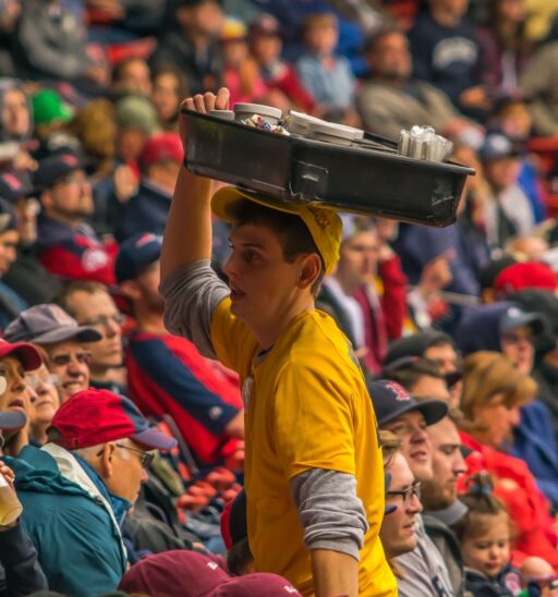A Fenway Park vendor sells hot dogs to Boston Red Sox fans at a baseball game.