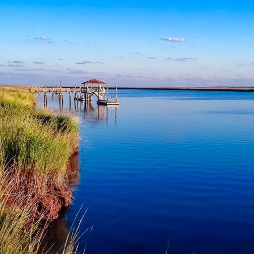 Dock on Daufuskie Island in Beaufort, South Carolina surrounded by marsh and deep blue waters from the intercoastal waterway.