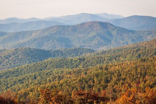 A view of the Blue Ridge mountains from the Appalachian Trail atop Round Bald in Tennessee-North Carolina. Layers of grasslands, forests, and distant mountain peaks.