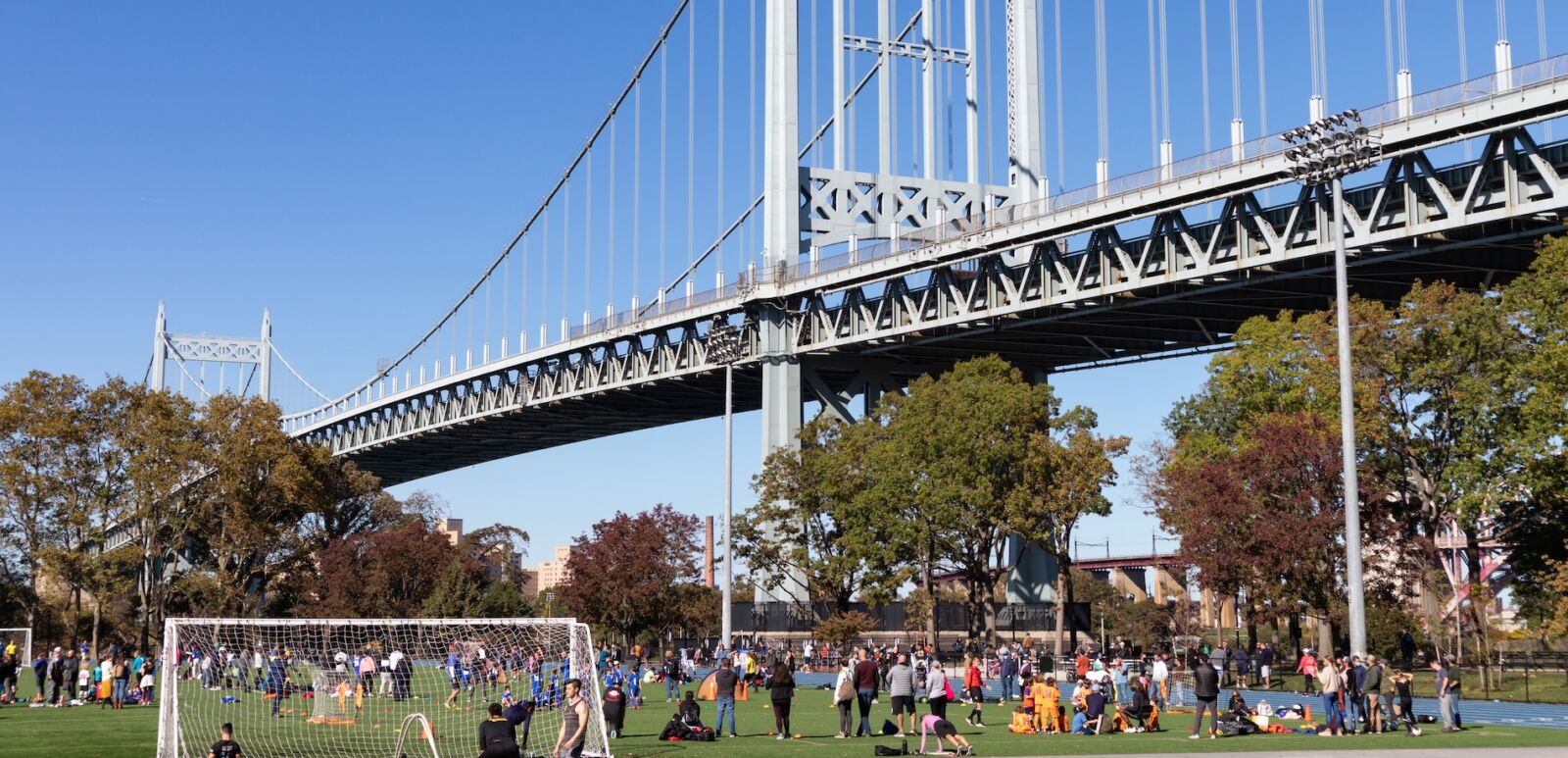 Astoria, Queens USA - October 17 2020: Athletic Field at Astoria Park Filled with People and the Triborough Bridge in Astoria Queens New York